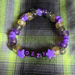 Beaded bracelet with 'OZZY' on a plaid fabric background
