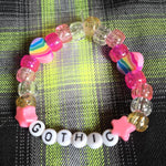 Colorful beaded bracelet with 'Gothic' on a plaid fabric background