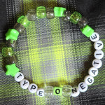 Bracelet with green and white beads on a checkered fabric background