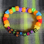 Colorful beaded bracelet with 'Motorhead' text on a plaid fabric background