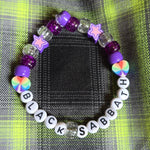 Bracelet with letter beads spelling 'Black Sabbath' on a checkered fabric background