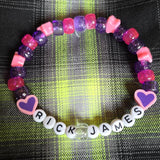 Colorful beaded bracelet with 'RICK JAMES' on a plaid fabric background