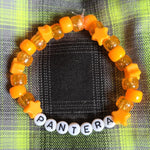 Orange beaded bracelet with letter beads on a plaid fabric background
