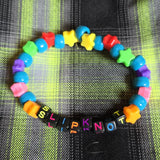 Colorful beaded bracelet with letter beads on a plaid fabric background