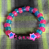 Colorful beaded bracelet with 'Korn' branding on a plaid fabric background